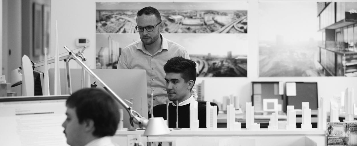 Owen Marhefka’s table is arranged with miniature designs of skyscrapers and Rodney Nelson looks at the Mac PC.