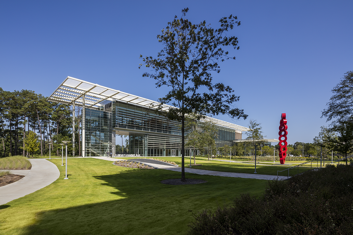 looking at the ExxonMobil Wellness Center with red sculpture on manicured lawn