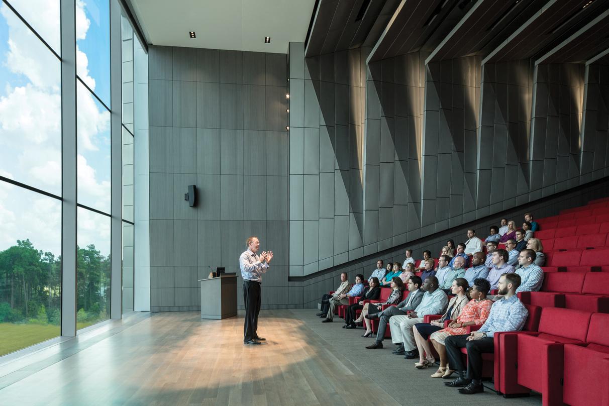 People inside an active lecture room naturally lit from the glass frame walls in ExxonMobil Energy Center, Houston, Texas. 