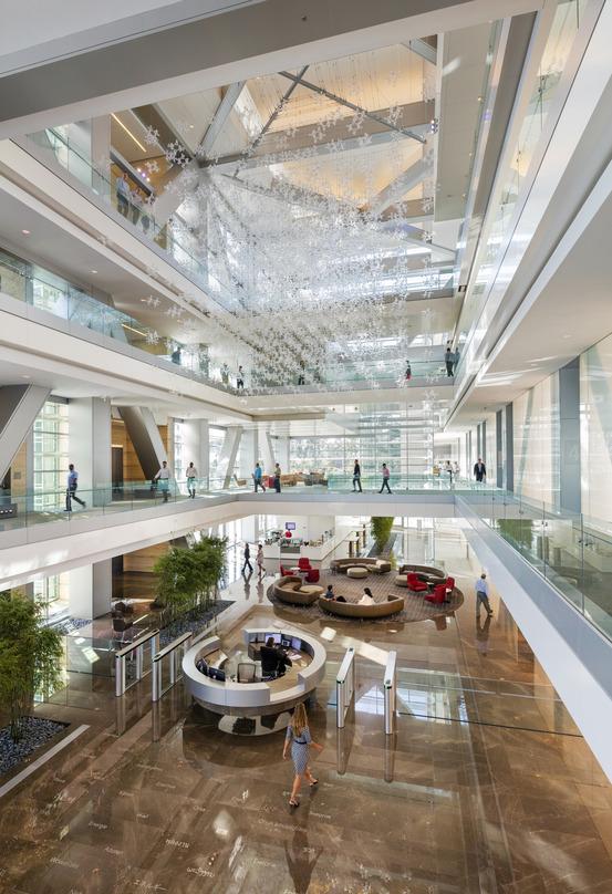 People walking inside ExxonMobil Energy Center, where a centrally suspended molecular crystal design adds aesthetic value.