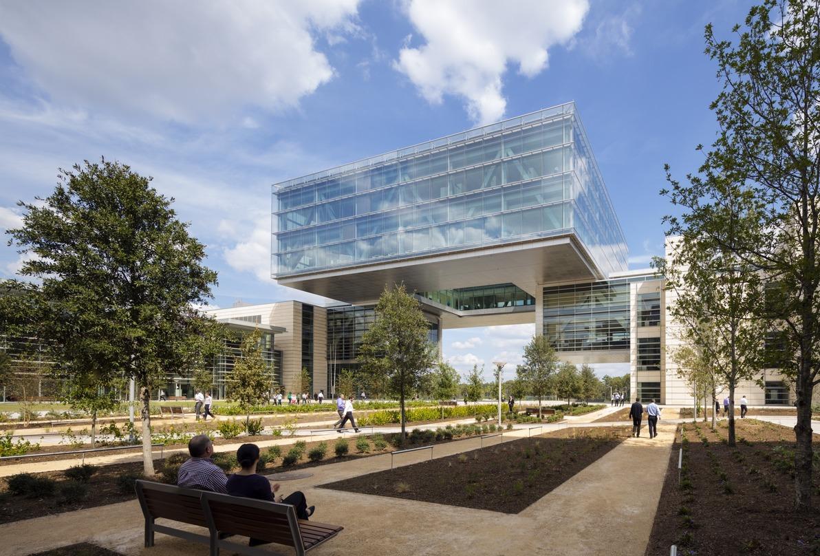 People walking around the pavement and relaxing on the park bench outside the ExxonMobil Energy Center, Houston, Texas.