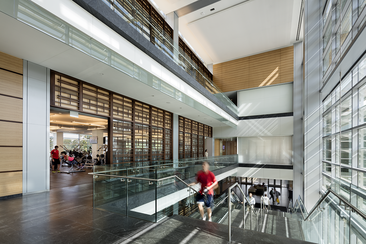 a person walking up the stairs and a view inside ExxonMobil Wellness Center