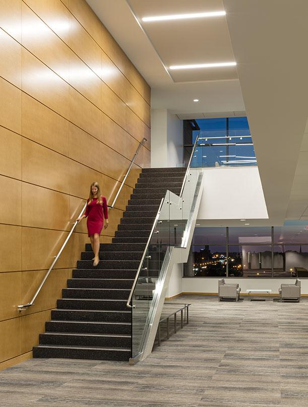 A woman in a red dress walking down a staircase in the Minnesota Senate Building