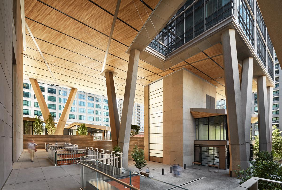 Open-air plaza at 2+U in Seattle – elevated office tower with V-shaped concrete supports, wood-clad ceilings, and vibrant pedestrian spaces.
