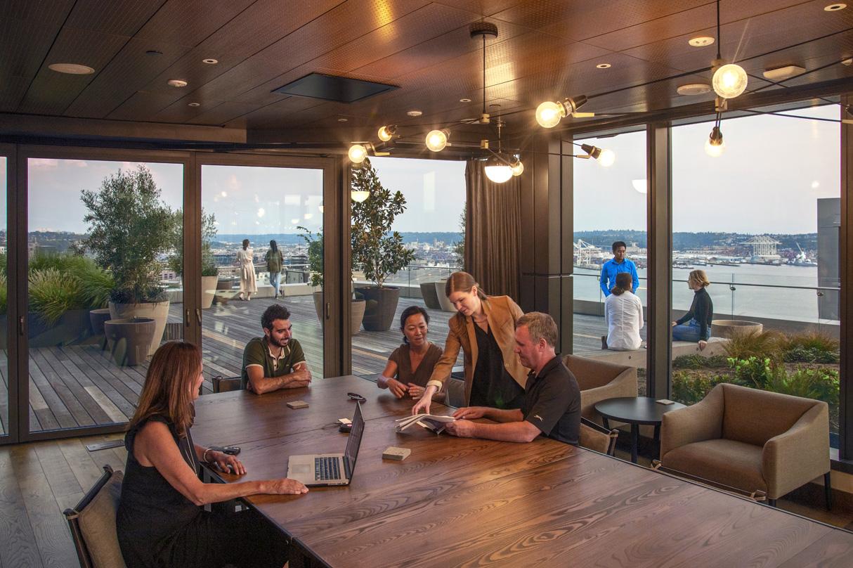 Team members collaborate in amenity space overlooking communal roof deck at 2+U.