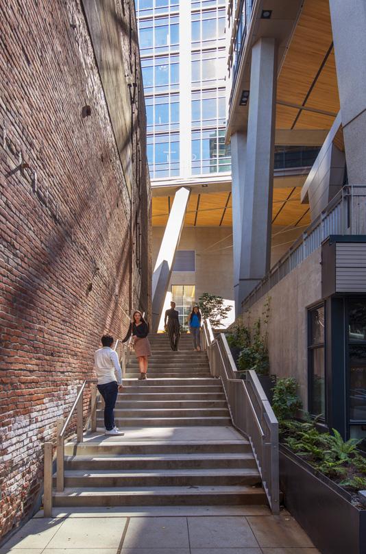 Pedestrian stairway at 2+U in Seattle – urban alley revitalization with exposed brick wall, concrete stairs, and connection to the elevated public plaza.