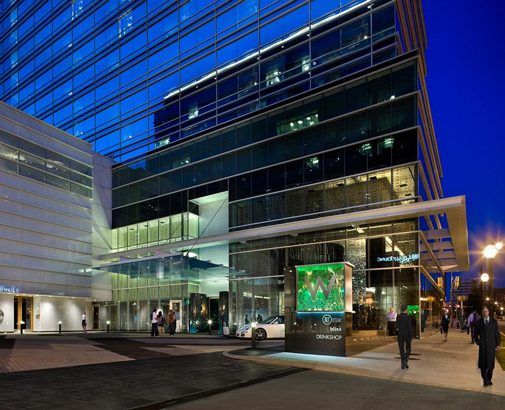 an evening view with a dark blue reflection off the glass facade, with storefronts and the main entrace W Atlanta-Downtown and The Residences