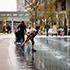 Children playing in the water fountain feature in the public courtyard of Takanawa Gateway City.