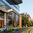 a person riding a bike on the sidewalk in front of the Akamai building in Cambridge Mass