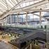 Interior view of the Takanawa Gateway City station under construction, featuring modern architecture with large glass windows, escalators, and platforms.