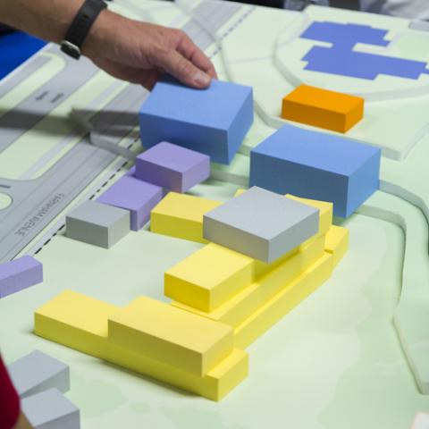 Employees stacking 3d designs on a 2d plan at their workplace.