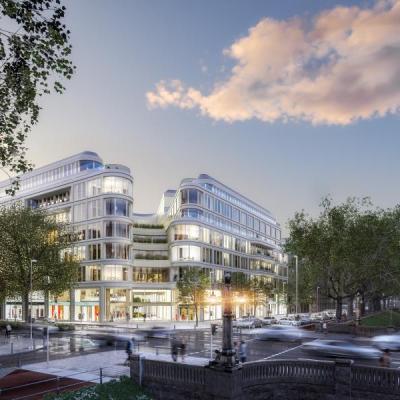 Evening view of Le Coeur Düsseldorf, a modern mixed-use development with glass facades and curved architecture, located along a busy urban boulevard with trees and historic buildings nearby.