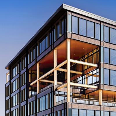 Evening view of T3 RiNo in Denver, a modern mass timber office building by Pickard Chilton, featuring glass façades and exposed structural elements.